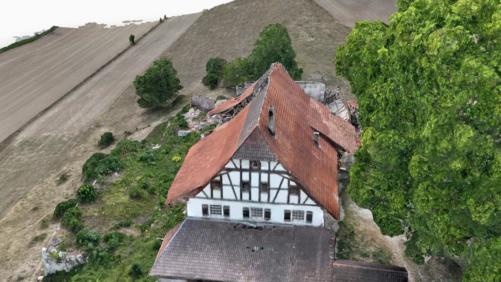 Schrägansicht eines texturierten 3D-Modells: Bauernhausdach mit Ziegelfläche, Fachwerkgiebel und eingestürztem Trakt, daneben verdeckt ein grosser Laubbaum die Gebäudeflanke