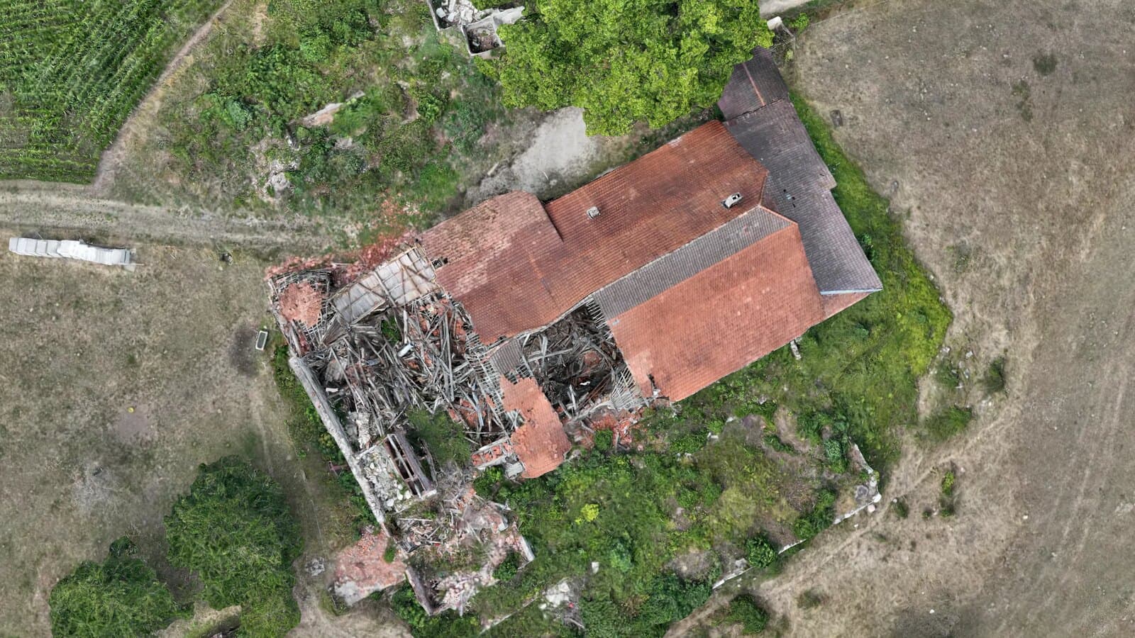 Senkrechte Ansicht eines Bauernhausdachs im texturierten 3D-Modell: geschlossene Ziegelfläche mit First, Kamin und Kehle, daneben ein eingestürzter Gebäudeteil mit freiliegendem Dachstuhl